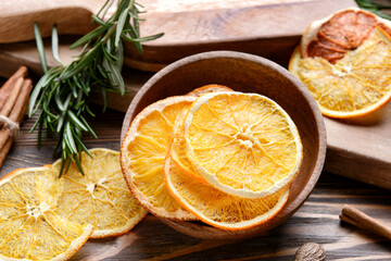 Bowl with dried orange slices on wooden background