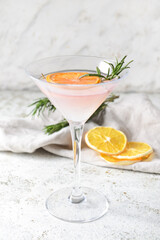 Glass of cocktail with rosemary and dried citrus fruits on light background