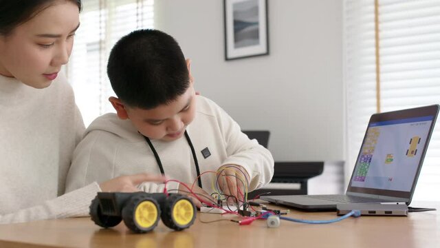 Young Asia Student Remotely Learn Online At Home With Parent In Coding Robot Car And Electronic Board Cable In STEM, STEAM, Mathematics Engineer Science Technology Computer Code In Robotics For Kids.