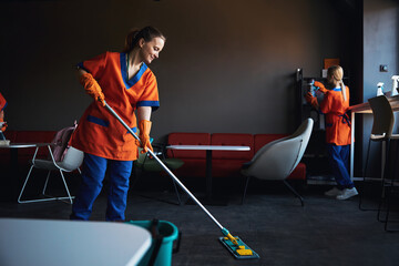 Smiling worker and her colleagues tidying up