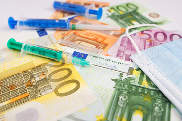 Protective medical mask, syringe vaccine and euro bills.