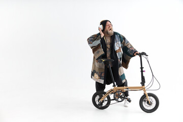 Fototapeta na wymiar Big fat tattoed caucasian man in kimono is holding little bicycle and smilling