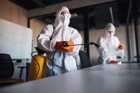 Trained janitorial staff sanitizing the surfaces of desks