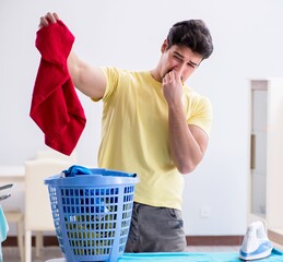 Handsome man husband doing clothing ironing at home