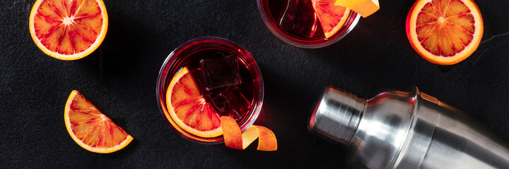 Negroni cocktails panorama with blood oranges on black