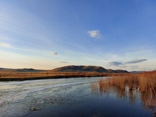 Melting River Ice and Water in Spring Sunset with Mountain on Horizon 