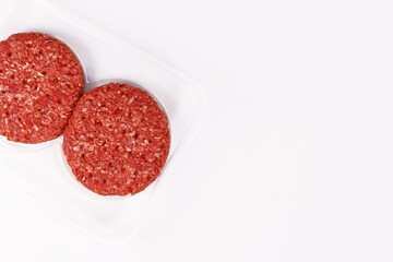 Raw round burger patties in package on white background with copy space
