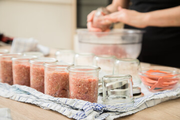 Frau füllt Hackfleisch aus Schwein und Rind roh in Einkochglas und Weckglas zum Einkochen Einwecken selbdstgemacht in Küche für Haltbarkeit und Vorrat