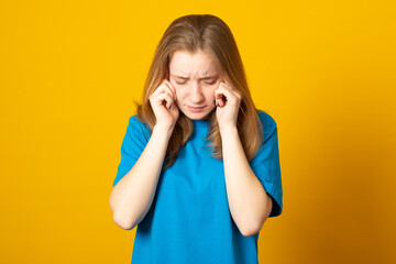 Young blonde girl wearing casual blue t-shirt over isolated background suffering from headache desperate and stressed because pain and migraine. Hands on head.