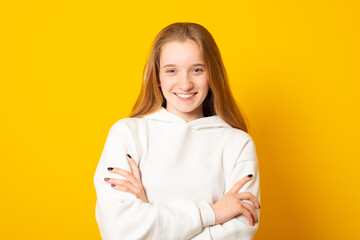 Obraz premium Beautiful teenage girl in a white hoodie cute smiling on yellow background.