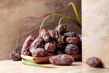 Dates fruit in a wooden dish on a beige ceramic table.