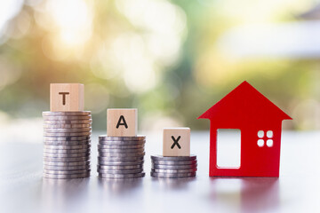 Taxes. Investments in real estate. Graph of the growth of a pile of silver coins and a red wooden house. Loans to buy a home. Wooden letters, block writing tax words.