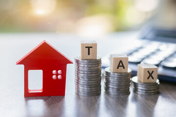 Taxes. Investments in real estate. Graph of the growth of a pile of silver coins and a red wooden house. Loans to buy a home. Wooden letters, block writing tax words.