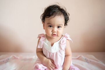 Fototapeta premium Portrait of a cute happy little Asian baby girl she look at camera, baby expression concept