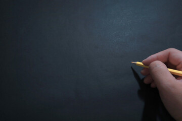 Naklejka premium Hand holding pencil in writing position, over dark black background