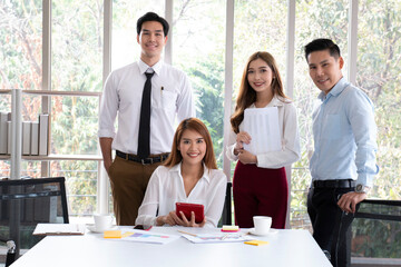 Group of young Asian business people working and communicating while at the office desk together with colleagues. Business people discussing over new business project in office.