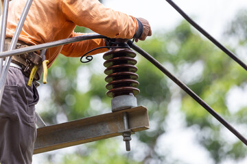 Rural electric poles are being repaired by electricians installing wires to connect. The tops of the electric poles are attached to the insulator. It is a job at a high rate.