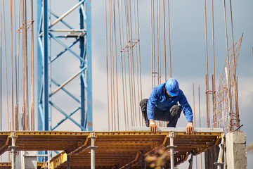 Real construction worker working on a high building and leveling floor for cementing.