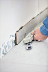 Ceramics tile man worker placing new tiles on the floor and wall.