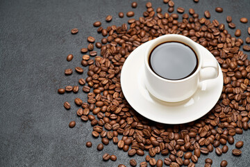 Cup of espresso coffee on roasted brown coffee beans on concrete background