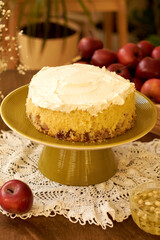 Sponge cake with apples garnished with whipped cream on a green plate on the table. Homemade pie