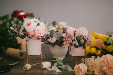 Beautiful floral composition with fresh flowers on wooden table in floristic studio.