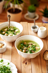 broccoli puree soup with sesame seeds, croutons and herbs. wooden background, side view