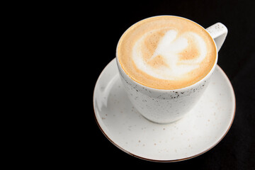Cup of caramel latte coffee on black background. Delicious sweet sugar coffee
