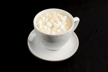 Cup of caramel latte coffee with marshmallows on black background. Delicious sweet sugar coffee