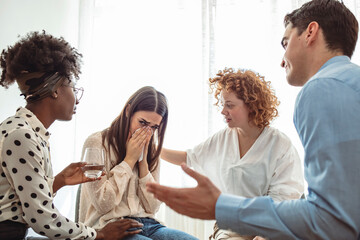 Support group gathering for a meeting. Young woman discussing with people at entrance hall. Males and females are sharing ideas during group therapy. Rehabilitation session activity