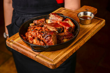 Assorted delicious grilled meat served in a frying pan on a wooden board.