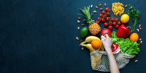 Human hand holding a string bag with fruits and vegetables
