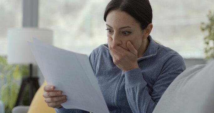 Shocked woman checking invoices at home