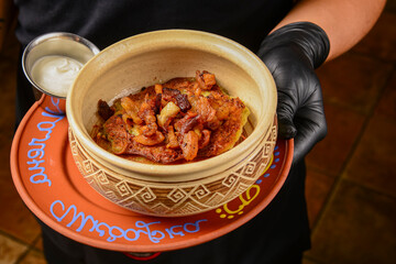 Delicious potato pancakes with roasted onions served in a ceramic bowl by waiter.