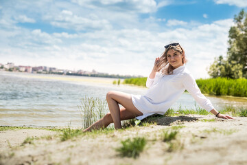 Naklejka na ściany i meble young beautiful woman in white dress enjoy nature near the lake, freedom