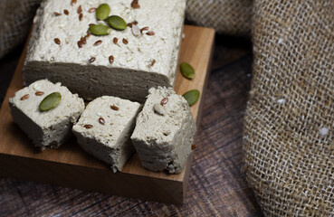 Halva close-up on a blackboard on a brown wooden background. Traditional oriental dessert sweet halva. Halva made from sunflower seeds. Side view, copyspace.