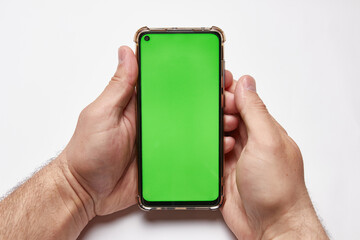 Male hand holds a phone with a green screen on a white background.