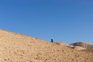 Silhouettes of tourists on the surface of the Judean Desert mountains.