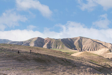 Silhouettes of tourists on the surface of the Judean Desert mountains.