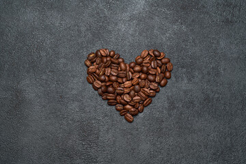 Heart shaped roasted coffee beans on dark concrete background