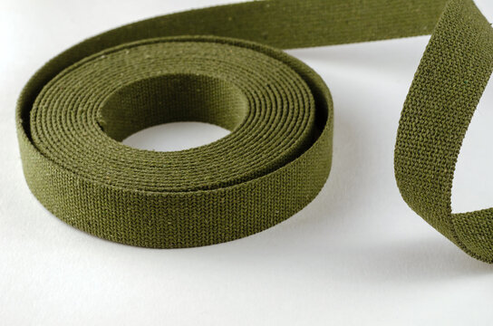 A roll of green cotton ribbon on a white background.