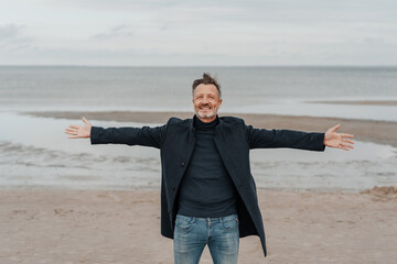 Man rejoicing standing on a beach with outstretched arms