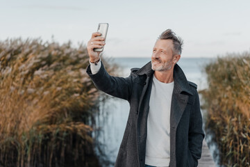 Man taking a selfie on his smartphone on a cold winter day