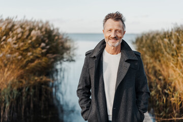 Trendy man in a warm overcoat posing outdoors at the coast