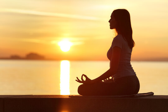 Profile of woman silhouette doing yoga exercise at sunset