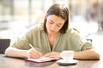 Woman writing on agenda in a coffee shop