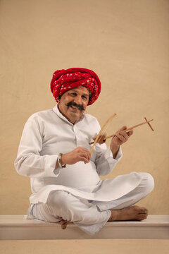 A VILLAGER HAPPILY SITTING AND PLAYING EKTARA INSTRUMENT	
