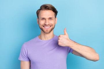 Photo of satisfied cheerful man beaming smile show thumb up look camera isolated on blue color...