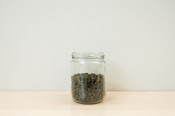 Dried herbal green tea leaves in a glass jar over wooden background