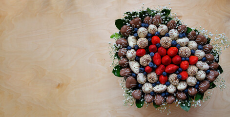 Delightful bouquet of strawberries, blueberries and leaves on wooden background.
